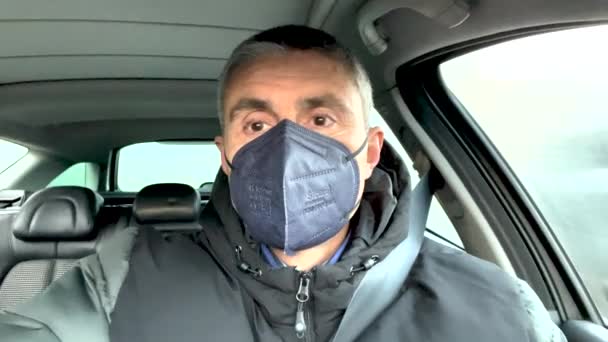Man in zijn auto rijden met een FFP2 mondmasker, proberen om ziekte te stoppen — Stockvideo
