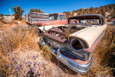 Mavi gökyüzünün altında paslı eski arabalar. Eski model araçlar.