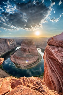 Günbatımında Horseshoe Bend, yaz mevsiminde Arizona. Güneş ışığı dağın arkasından geliyor.