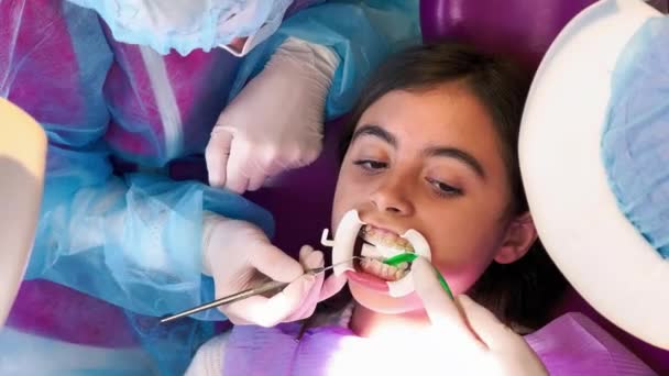 Een jong meisje in de tandartsstudio. Inbrengen van tandheelkundige apparatuur — Stockvideo