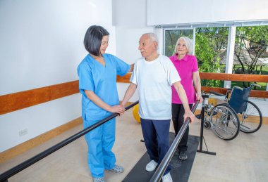 Asyalı antrenörün yardımıyla spor salonunda gülümseyen birkaç son sınıf öğrencisi. Emekli yaşlılar hayatlarını en iyi şekilde yaşıyorlar.