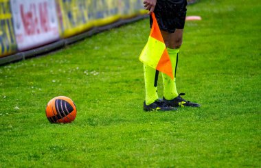 Bayrak ve futbol topuyla futbol hakemi asistanı.