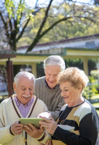 Três Idosos Sorrindo Livre Brincando Com Tablet Idosos Aposentados Vivendo — Fotografia de Stock