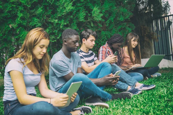 Colegial Multi Estudantes Étnicos Relaxante Usando Aparelhos Eletrônicos Livre — Fotografia de Stock