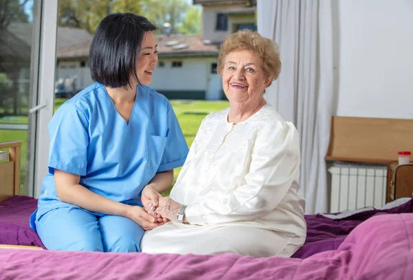 リハビリクリニックで看護師と笑顔の白人女性先輩 引退した高齢者は人生を最善を尽くして生きている — ストック写真