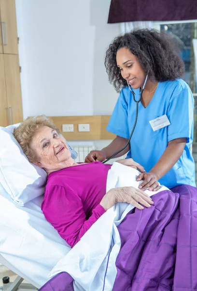 在医院里 白种人老年女性对着非洲女医生笑着 退休的老年人过着最好的生活 — 图库照片