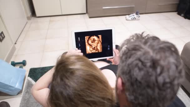 Echografie van de 4e maand foetus gezien door toekomstige ouders op de tablet — Stockvideo