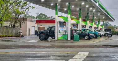 Otoyoldaki benzin istasyonunda bir sürü araba var. Araçları benzinle dolduruyorum.