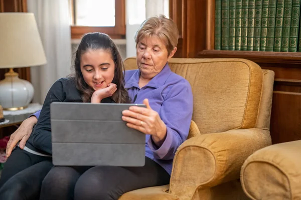 Küçük Kız Büyükannesiyle Oturma Odasında Tablet Izlerken Rahatlıyor — Stok fotoğraf