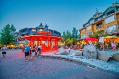 Whistler, Kanada - 11 Ağustos 2017: Turistler gün batımında şehir merkezini ziyaret ederler. Whistler ünlü bir turistik dağ beldesidir.