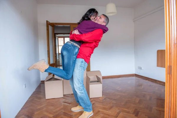 Husband Jeans Lifting His Wife Surrounded Cardboard Boxes Excited Move — Φωτογραφία Αρχείου