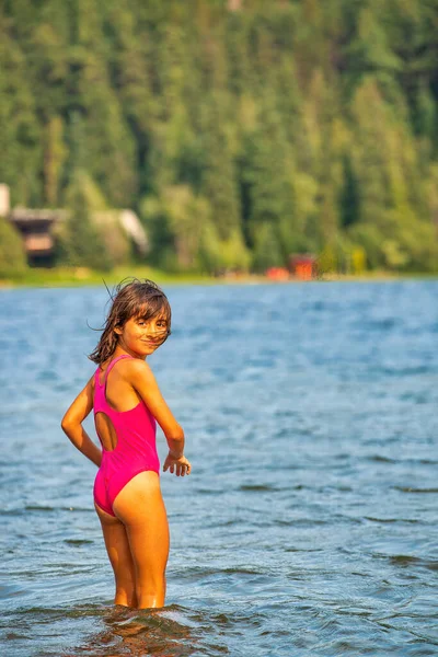 少女は山のシナリオで冷たい湖の水に足を浸し — ストック写真