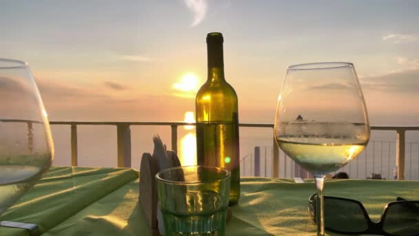Bicchiere di vino e bottiglia al tramonto con panorama dell'isola sullo sfondo. Concetto vacanza — Video Stock