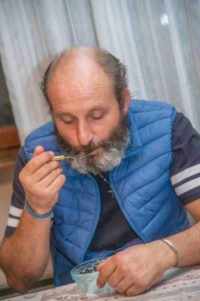 Man with beard eating ice cream indoor