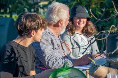 Büyükbaba torunlarına dizüstü bilgisayarın nasıl kullanılacağını anlatıyor.