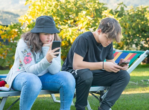 Couple Young Boy Girl Seated Garden Playing Smartphones — Photo