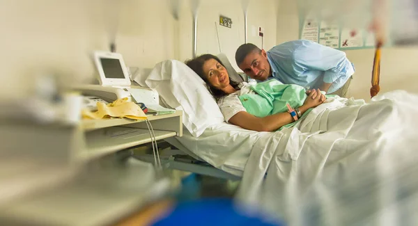 Husband and wife at the hospital after giving birth to their newborn child.