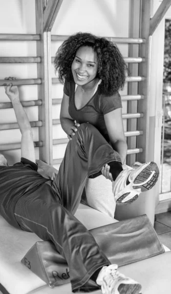 Nurse assisting elder people in a rehab facility gym.