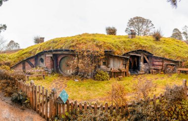 Beautiful Hobbiton Movie Set Village in New Zealand with autumn colors. Wooden homes in the park.
