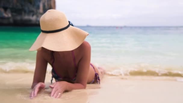 Χαλαρωμένη Όμορφη Γυναίκα Φορώντας Ένα Ψάθινο Καπέλο Ξαπλωμένη Στη Θάλασσα — Αρχείο Βίντεο