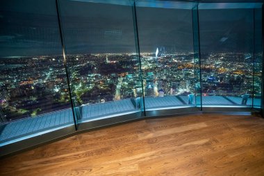 Yüksek bir kulenin tepesinden gece havası manzarası. Şehir ışıkları gözlüklerin ardında..