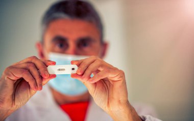 Erkek doktor, kovid testinin negatif sonuçlarını gösteriyor.