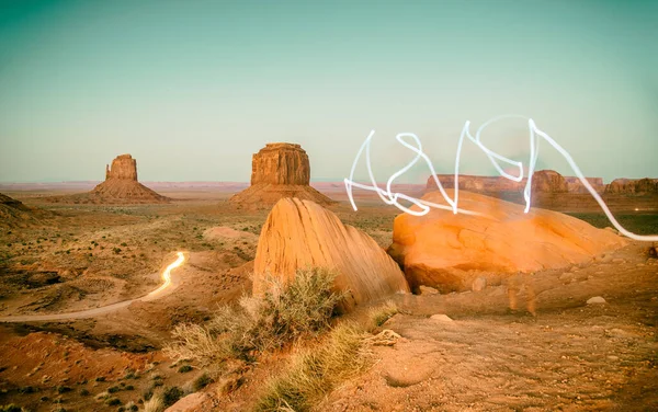 Making light signs with torch in the Monument Valley night