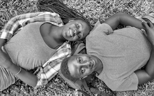 高中时 一对年轻的非洲夫妇在公园的草地上悠闲自在地躺着 — 图库照片