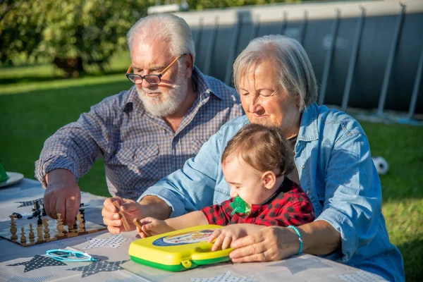 在阳光明媚的下午 祖父母和孙子孙女们在户外玩棋盘游戏 — 图库照片