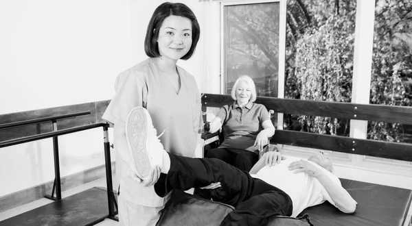 Nurse assisting elder people in a rehab facility gym.