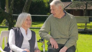 Couple of active seniors with health issues having conversation outdoor.