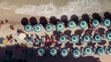 aerial footage of sunshades with tanning people on beach on sunny day