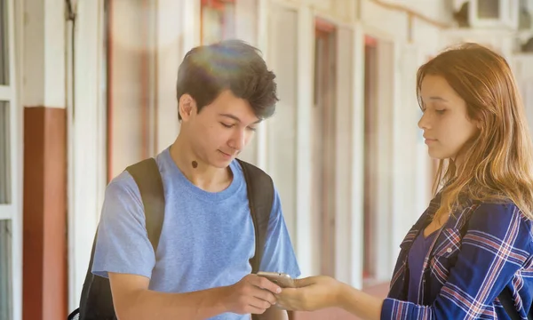 在学校走廊里 一对白人青少年夫妇在看智能手机 — 图库照片