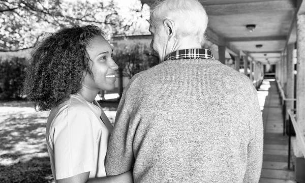 Nurse assisting elder man outdoor.