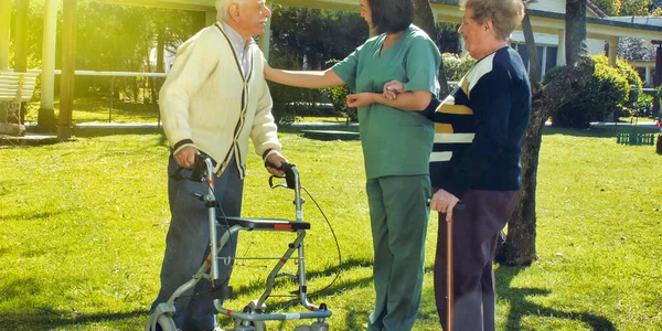 年轻的亚洲女护士和退休的老夫妇在室外微笑 在医院花园与他们交谈 — 图库照片