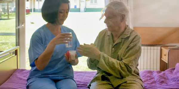 Jovem Asiático Médico Feminino Ajudando Idosos Aposentado Homem Tomando Pílula — Fotografia de Stock