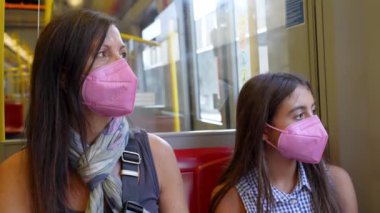 Kızıyla metroda seyahat eden bir kadın. Salgın yüzünden maske takan bir robot..