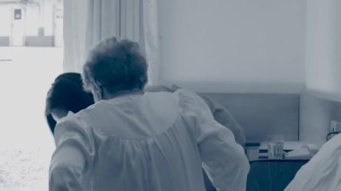 Asyalı hemşirenin yardımıyla hastanede yatan yaşlı bir kadın..