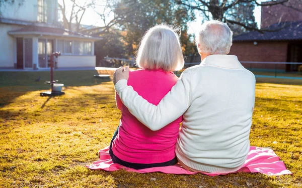 Elder couple outdoor relaxing seated on the garden.