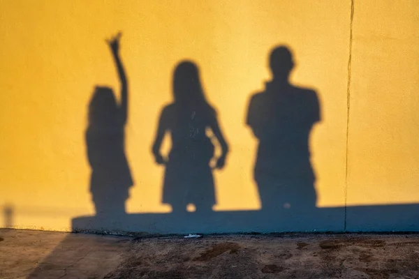 Shadows of a family of three people on the wall at sunset time. Group of human shadows on the stone wall background.