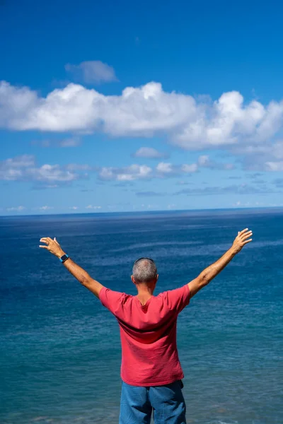 Man with open arms embracing nature on a beautiful island, back view.