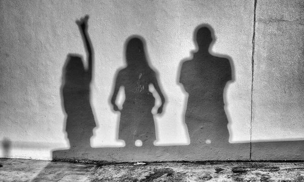 日落时分 一个三人家庭的阴影出现在墙上 石墙背景上的一组人影 — 图库照片