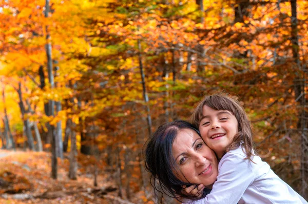 Happy mother and daughter walking along a trail in foliage season.