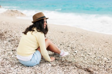Sahilde oturmuş ve denizde seyir güzel bir genç kadın