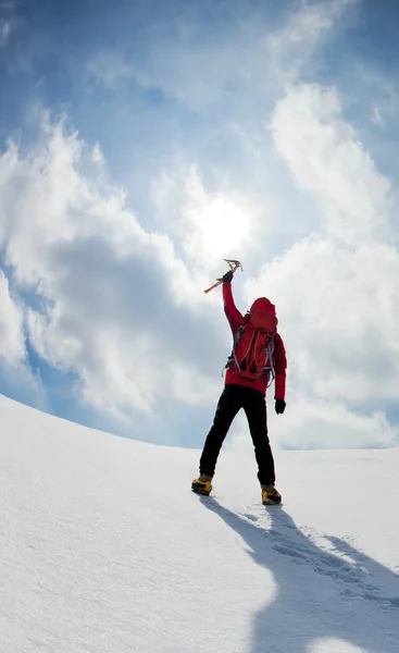 Bergbeklimmer bergop te wandelen langs een besneeuwde helling — Stockfoto