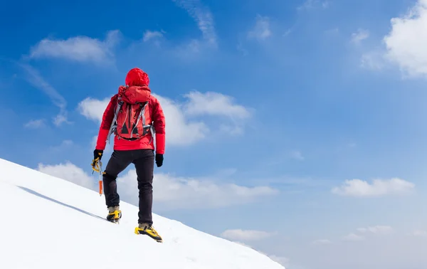 Alpinista che cammina in salita lungo un pendio innevato . — Foto Stock