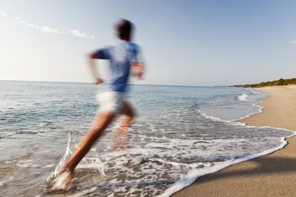 Giovane che corre su una spiaggia . — Foto Stock