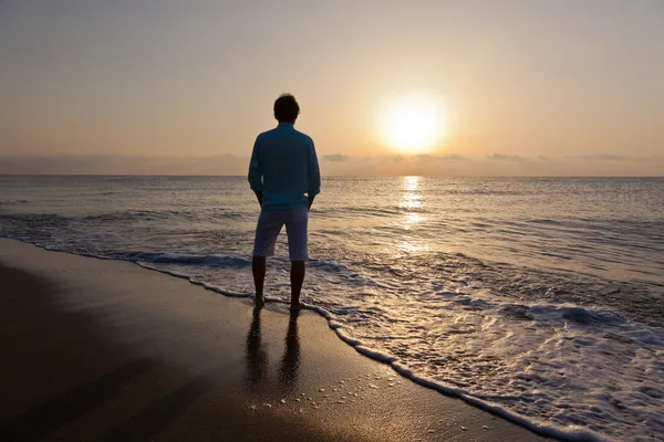 Homme seul sur la plage regardant le coucher du soleil — Photo