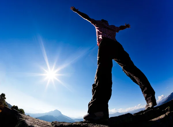 El hombre abre sus brazos en el sol contra el cielo azul . — Foto de Stock