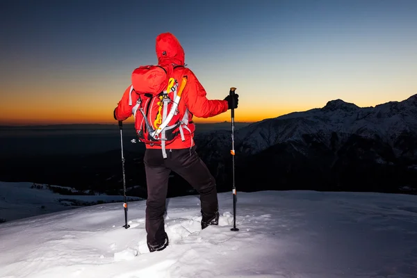 Senderismo de invierno: el hombre se para en una cresta nevada mirando el atardecer — Foto de Stock